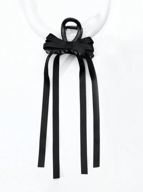 Melna satīna matu spīlīte ar garu bantīti meitenēm uz balta fona