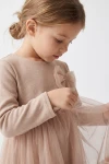 Bēša svētku tilla kleita meitenēm Iga – tilla bantīte un trikotāžas augšdaļa ar garu piedurkni, tuvplāns no sāniem